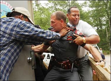 Narragansett Indian Chief Sachem Matthew Thomas, right, tries to hold back a Rhode Island State Police officer from entering the Narragansett Indian Smoke Shop in Charlestown, RI