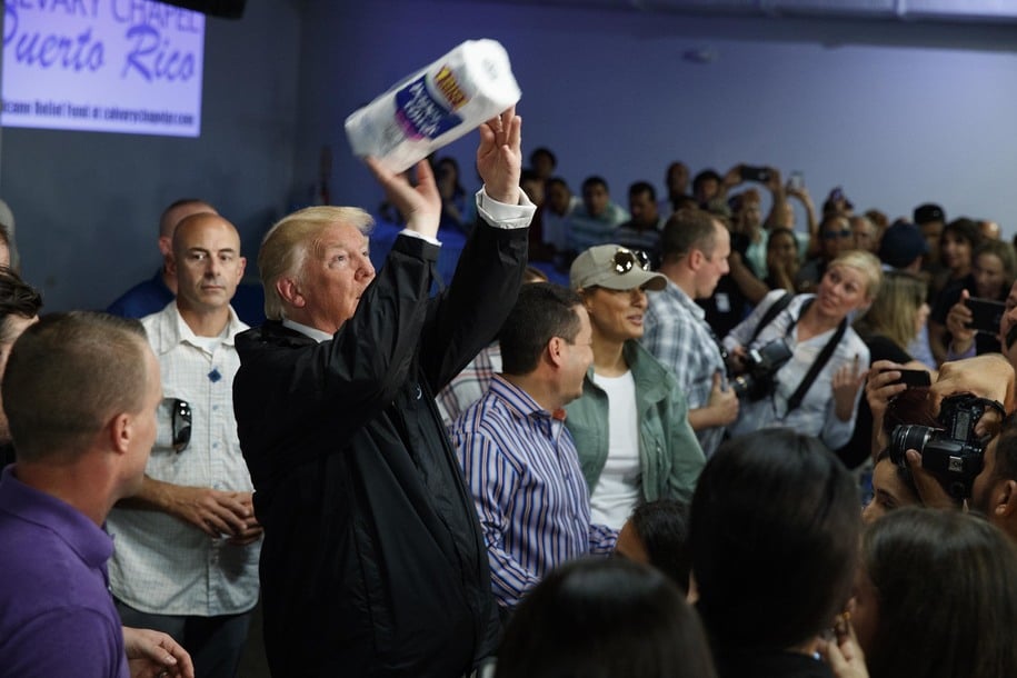 President Donald Trump tosses paper towels into a crowd as he hands out supplies at Calvary Chapel, Tuesday, Oct. 3, 2017, in Guaynabo, Puerto Rico. Trump is in Puerto Rico to survey hurricane damage. (AP Photo/Evan Vucci)